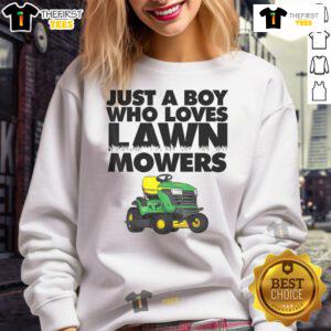 Boy wearing a 'Just A Boy Who Loves Lawn Mowers' sweatshirt, smiling in a garden with a lawn mower.