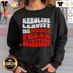 Alt Text: Official Karoline Leavitt in a stylish white blouse and sweatshirt, showcasing her role as Press Secretary.
