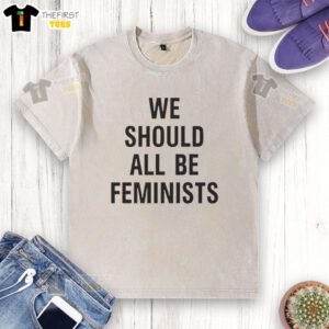 Alt Text: Pretty We Should All Be Feminists washed t-shirt displayed on a wooden table, promoting gender equality and empowerment.