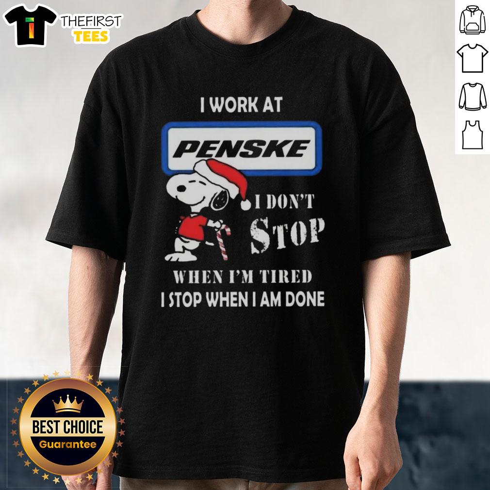 Alt Text: Cute Snoopy Christmas T-shirt featuring the phrase I work at Penske Corporation, I don't stop when I'm tired.