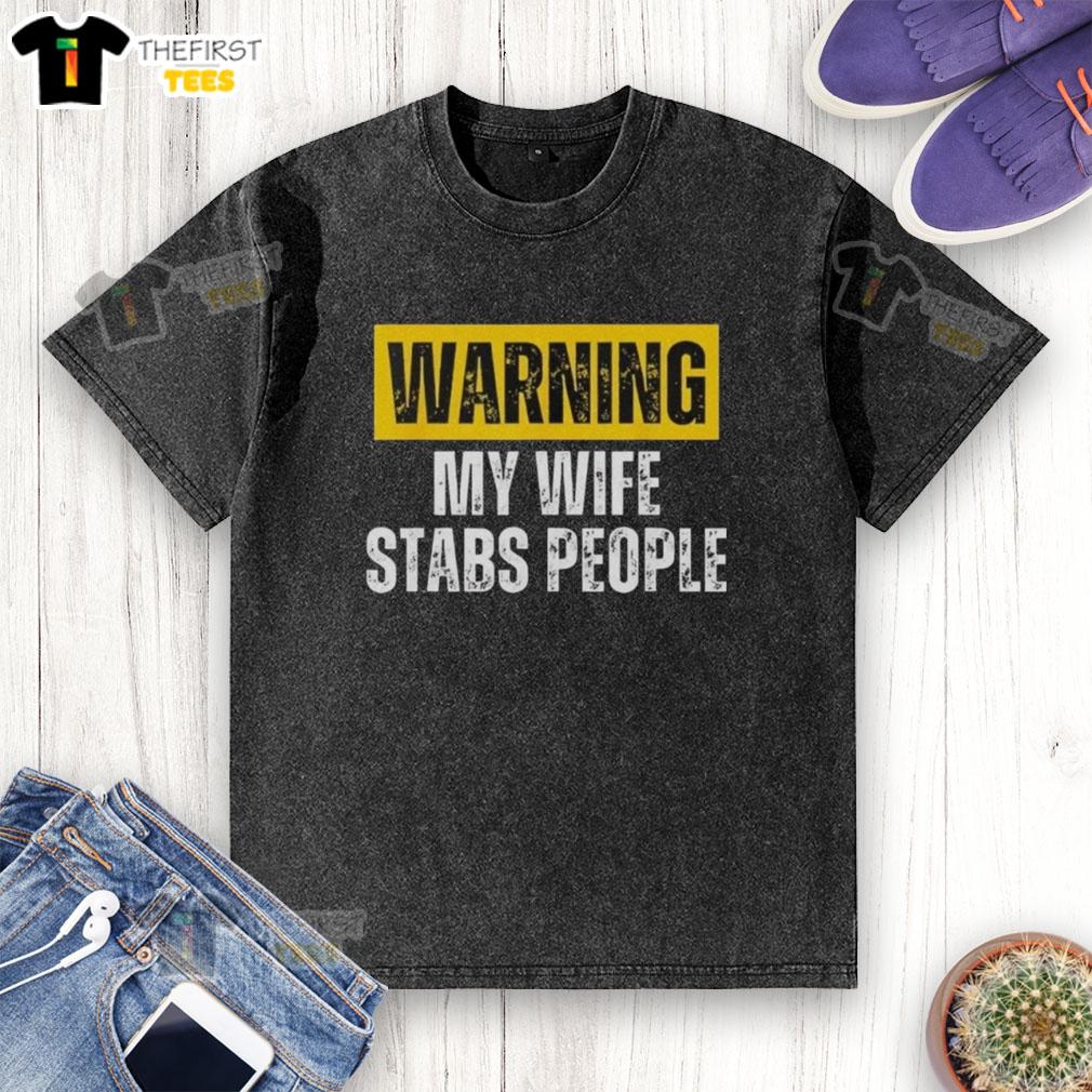 Vintage washed T-shirt featuring 'Official Warning: My Wife Stabs People' graphic, perfect for humorous apparel lovers.
