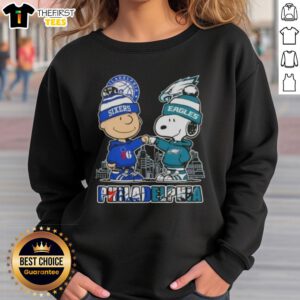 Pretty Charlie Brown fist bump with Snoopy, featuring Philadelphia skyline, 76ers and Eagles logo on cozy sweatshirt.