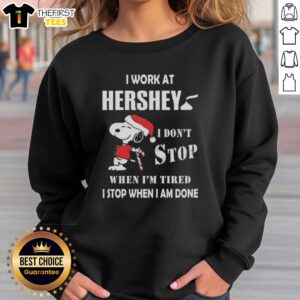 Cozy Christmas sweatshirt featuring Snoopy with 'I Work At Hershey, I Dont Stop When Im Tired' slogan.