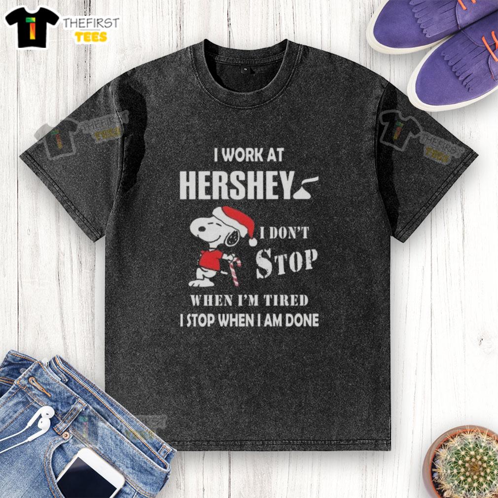 Alt Text: Top Snoopy t-shirt featuring 'I work at Hershey, I dont stop when Im tired, I stop when Im done' design for Christmas.