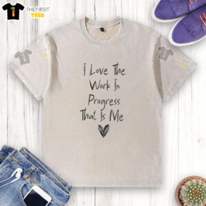 Alt Text: Original I Love The Work In Progress That Is Me washed t-shirt displayed on a wooden background, perfect for casual wear.