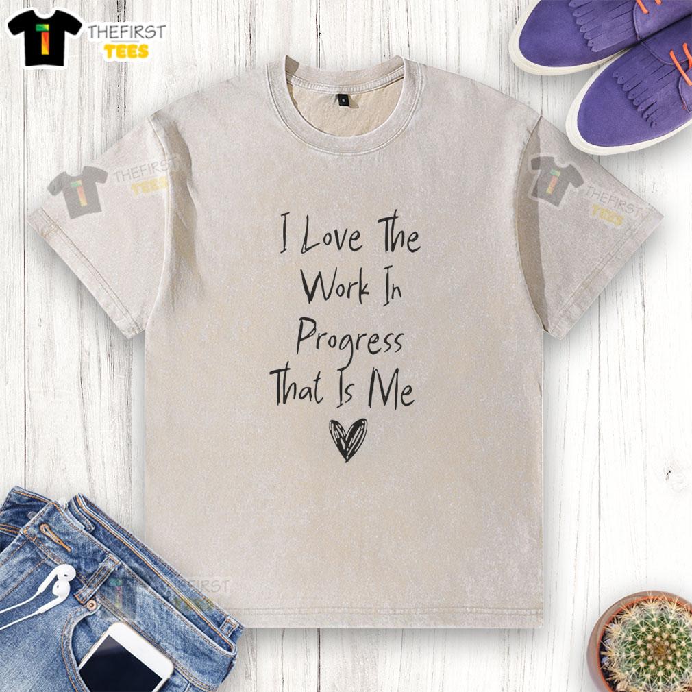 Alt Text: Original I Love The Work In Progress That Is Me washed t-shirt displayed on a wooden background, perfect for casual wear.